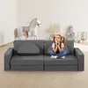 A young girl sits on a modular sofa in a playroom with toys in the background. Náhled obrázku produktu