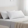 Two white pillows on a bed with a light-colored headboard and a knitted throw blanket. Produktbild-Vorschau