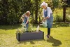 An adult and a child are watering plants in a raised garden bed in a backyard. Náhľad obrázku produktu