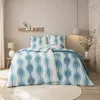 A bedroom scene with a bed made up with a blue and white wave-patterned duvet cover and pillows. Produktbild-Vorschau