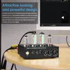 A black audio preamplifier with glowing vacuum tubes sits on a wooden table next to a computer monitor. Podgląd zdjęcia produktu