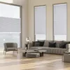 A modern living room with large windows, a sofa, armchair, and coffee table, showcasing the blinds. Produktbild-Vorschau