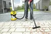 A person is using a wet/dry vacuum cleaner to clean a paved patio area. Produktbild-Vorschau