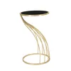 A modern side table with a black circular top and a gold, sculptural base. Anteprima dell’immagine prodotto