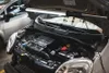The hood of a car is open, revealing the engine compartment, with a work light illuminating the area. Produktbild-Vorschau