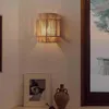 A wall lamp made of jute rope is mounted on a wall above a framed picture and a decorative vase. Voir les images du produit