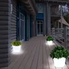 Illuminated planters on a wooden deck at dusk, next to a log cabin. Produktbild-Vorschau