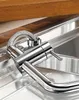 A close-up view of a chrome faucet and its flexible hose, resting on a stainless steel sink. Produktbild-Vorschau