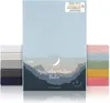 A product image showing a light blue fitted sheet with a mountain landscape design on its packaging, and stacks of fitted sheets in various colors on either side. Produktbild-Vorschau