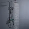 A modern shower system with a square rain shower head and a handheld shower head, mounted on a gray wall. Water is actively flowing from the rain shower head. Podgląd zdjęcia produktu