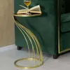 A gold side table with a book and a glass of wine on it, next to a green sofa. Anteprima dell’immagine prodotto