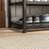 A close-up view of a shoe rack with several pairs of shoes on it, placed on a wooden floor with a rug in the foreground. Podgląd zdjęcia produktu