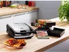 A kitchen counter with a waffle maker, waffles, and packaging for waffle plates. Voir les images du produit