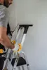 A person is using a ladder to measure a wall. Anteprima dell’immagine prodotto