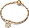 A close-up shot of a gold-colored bracelet with a charm. Podgląd zdjęcia produktu