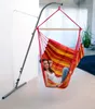 A woman is relaxing in a colorful hammock chair indoors, with a stand supporting it. Produktbild-Vorschau