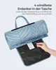 A hand is shown holding a small metal tool, about to insert it into a pocket on a rolled-up picnic blanket. Produktbild-Vorschau