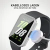 A smartwatch with a protective case is shown being wirelessly charged. Produktbild-Vorschau