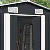 Close-up view of the upper part of a dark grey metal shed with white trim, showing two ventilation grilles and the entrance with a ladder and broom inside. Náhled obrázku produktu