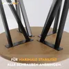 Close-up view of black metal table legs being attached to a round wooden tabletop with screws. Anteprima dell’immagine prodotto