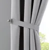 A close-up of a gray curtain held back by a tie-back. Produktbild-Vorschau