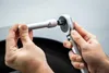 A close-up shot of a person's hands holding a socket wrench and an extension bar, preparing to connect them. Anteprima dell’immagine prodotto