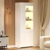A modern white display cabinet with LED lighting, showcasing decorative items and books, next to a wooden wall with decorative pendant lights. Produktbild-Vorschau