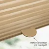 Close-up of a beige pleated blind with a handle, with a blurred green and white background suggesting an outdoor view. Produktbild-Vorschau