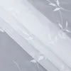 A close-up view of white sheer curtains with embroidered leaf patterns, layered over a light gray background. Produktbild-Vorschau