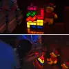 Two children are playing with a stackable Tetris-like light in a dimly lit room, with stuffed animals and books in the background. Produktbild-Vorschau