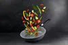 Vegetables are being tossed in a frying pan against a dark background. Produktbild-Vorschau