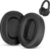 Two black ear pads for headphones are shown in the foreground, with a pair of black headphones in the background. Produktbild-Vorschau