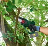A person is using a cordless pruning saw to cut a branch off a tree. Produktbild-Vorschau