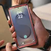 A person is holding a smartphone with a red protective case. Náhled obrázku produktu