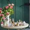 Easter-themed figurines and tulips arranged on a table in front of a green wooden door. Náhled obrázku produktu