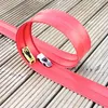Rote flexible Spielzeugauto-Strecke mit einer Schleife, zwei Spielzeugautos, einem gelben und einem weißen, auf einem Holzdeck Anteprima dell’immagine prodotto