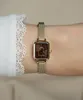 A close-up shot of a woman's wrist wearing a gold Daniel Wellington watch. Voir les images du produit