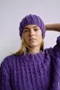 A woman wearing a purple knitted sweater and hat. Produktbild-Vorschau