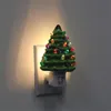 A ceramic Christmas tree night light plugged into a wall outlet. Náhľad obrázku produktu