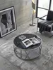 Runder Couchtisch mit silbernem Metallgestell aus der Vogelperspektive neben einem schwarzen Ledersessel auf einem silbergrauen Seidenteppich._#sku_SAFWL6.674# Produktbild-Vorschau