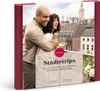 A couple embracing on a balcony overlooking a city skyline, with a gift box overlay. Produktbild-Vorschau