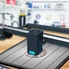 A close-up view of a laser engraving machine's honeycomb working table with a decorative wooden piece being engraved. Náhled obrázku produktu