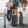 Two people are standing at what appears to be an airport or train station, looking at a map, with luggage beside them. Produktbild-Vorschau