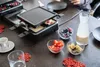 Der ausziehbare Raclette-Grill von Unold schmilzt Käse auf der Tischplatte, umgeben von Schüsseln mi Produktbild-Vorschau