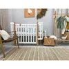 A nursery room setting with a crib, chair, and clothing rack. Produktbild-Vorschau