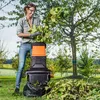 A woman is using a garden shredder outdoors in a garden setting. Produktbild-Vorschau