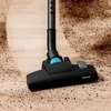 A close-up shot of a vacuum cleaner head cleaning a wooden floor with dirt. Produktbild-Vorschau