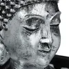 A close-up of a silver Buddha statue's face. Náhled obrázku produktu