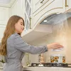 A woman is cooking in a modern kitchen with a range hood. Voir les images du produit