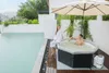 A couple relaxing in a hot tub next to a swimming pool on a cloudy day. Produktbild-Vorschau